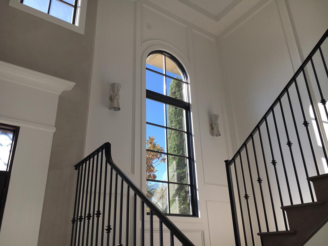 A staircase with a wrought iron railing and a large window