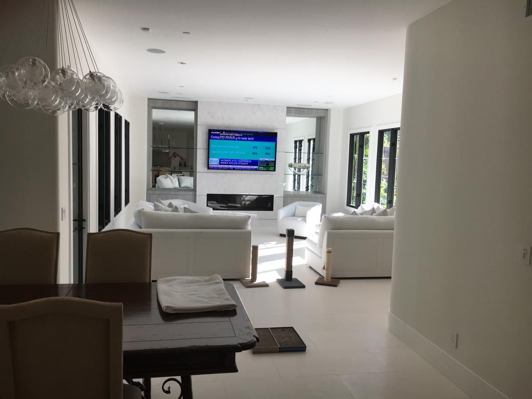 A living room with a table and chairs and a flat screen tv on the wall.