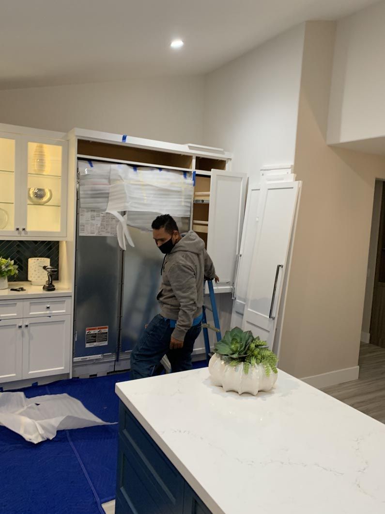 A man is installing a refrigerator in a kitchen.
