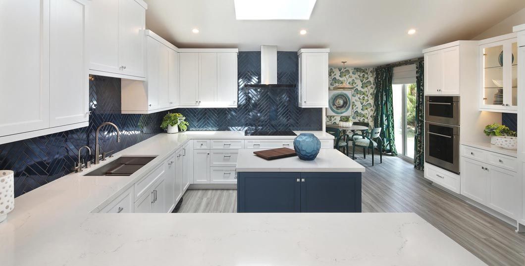 A kitchen with white cabinets and blue cabinets and a large island in the middle.