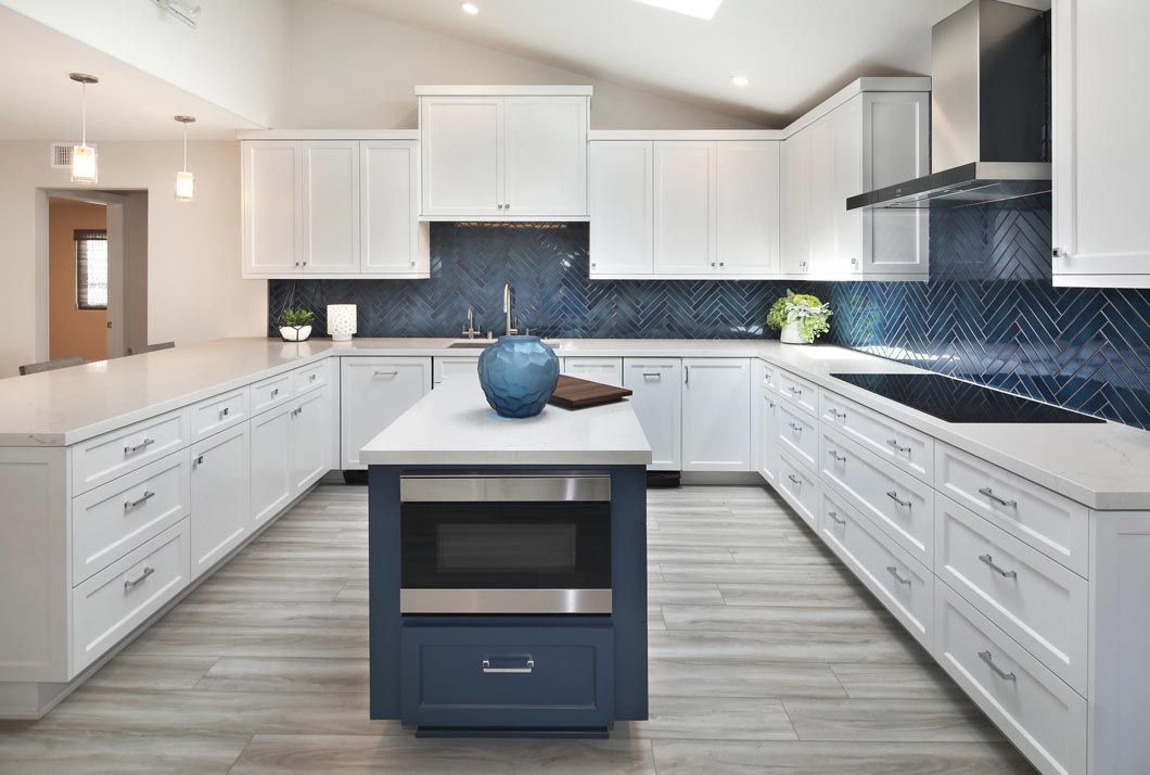 A kitchen with white cabinets and a blue island in the middle.