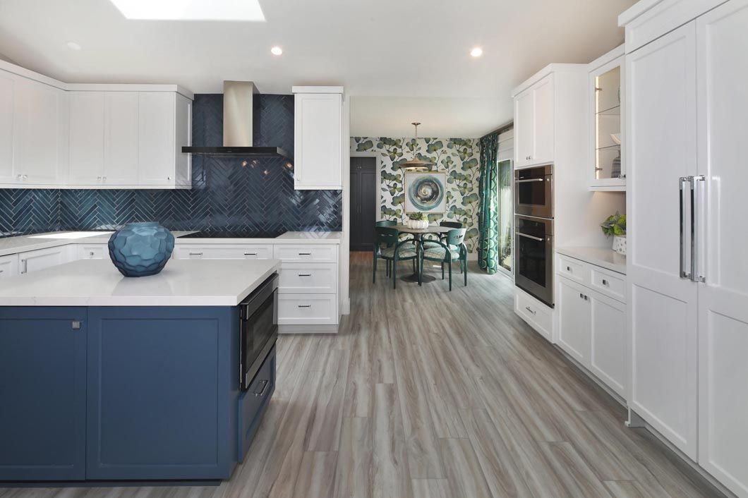 A kitchen with blue cabinets , white cabinets , hardwood floors and a blue island.