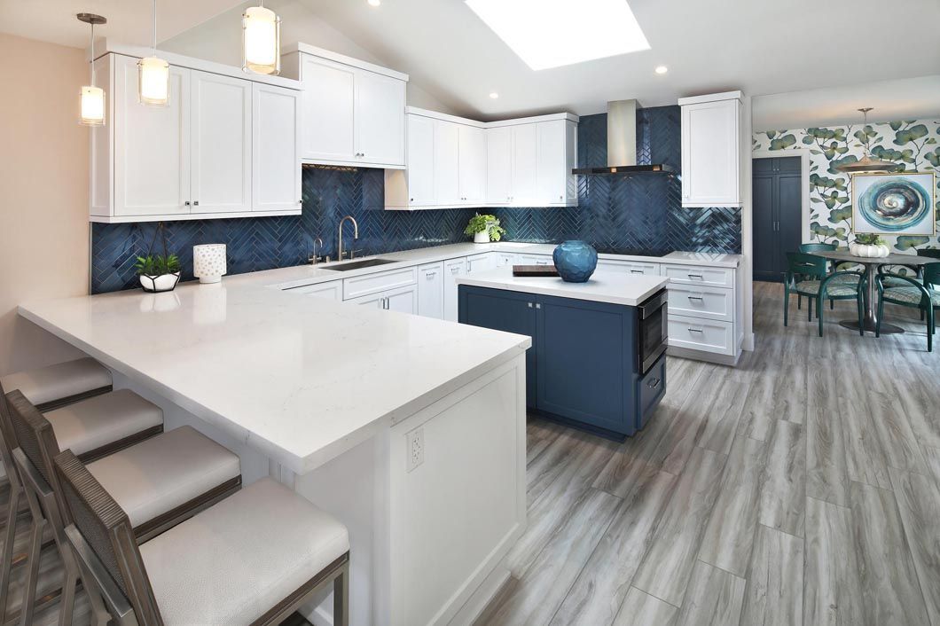 A kitchen with white cabinets , blue counter tops , and a large island.