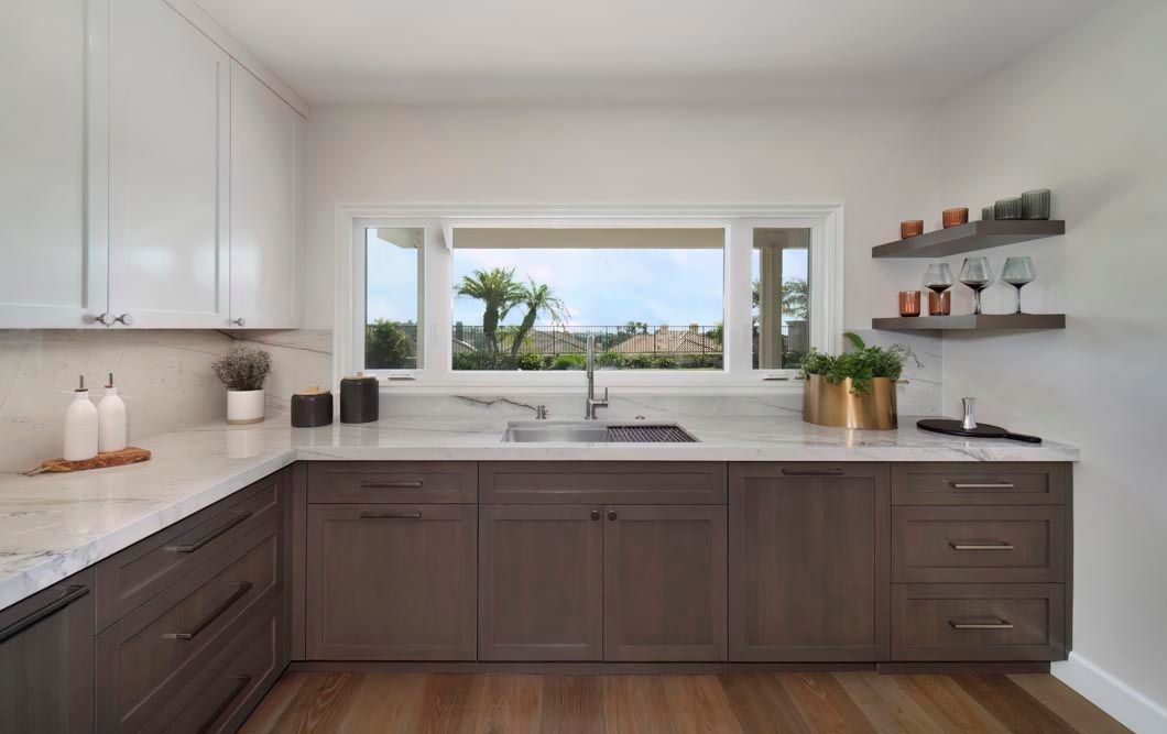 A kitchen with a sink , cabinets , and a window.