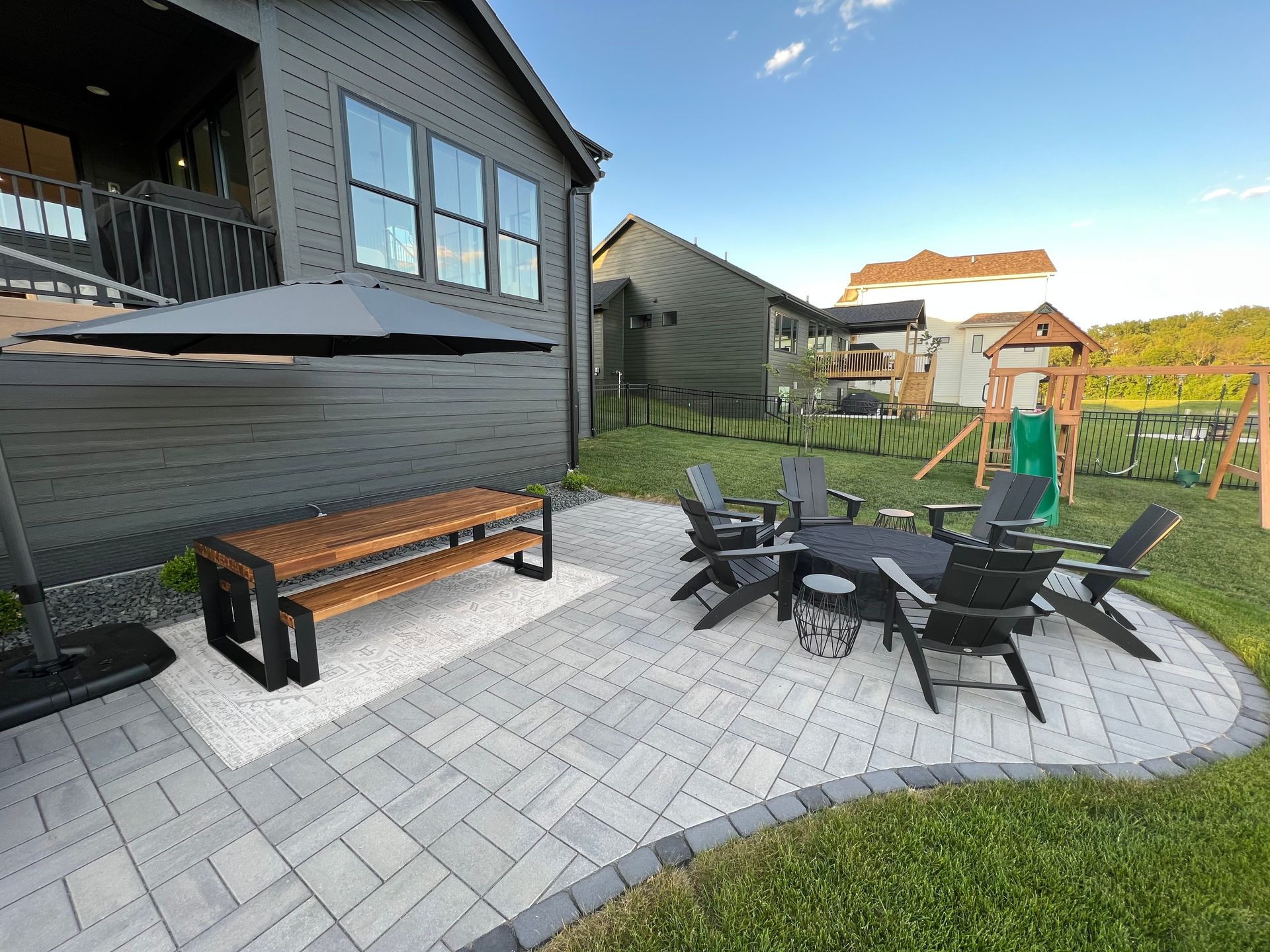 A stone patio with a wooden picnic table, a fire pit.