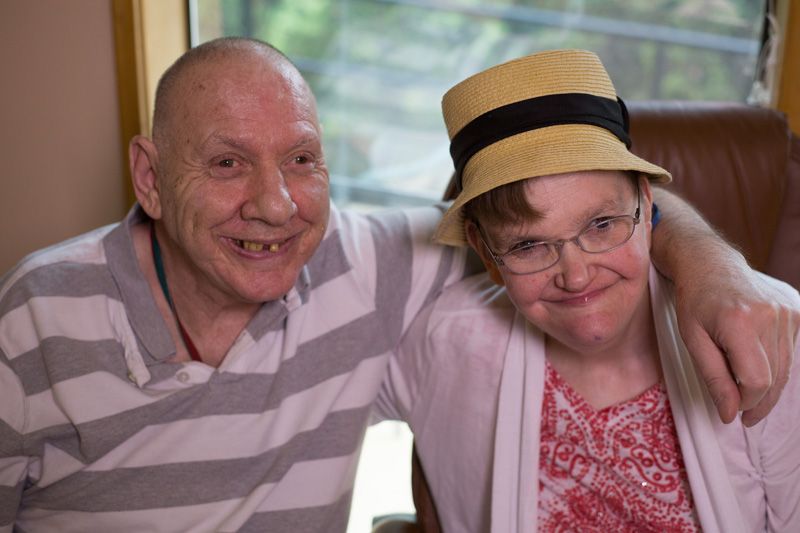 A man and a woman are posing for a picture together . the woman is wearing a straw hat.