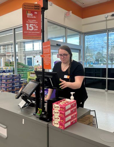 A woman is standing at a cash register in a store.