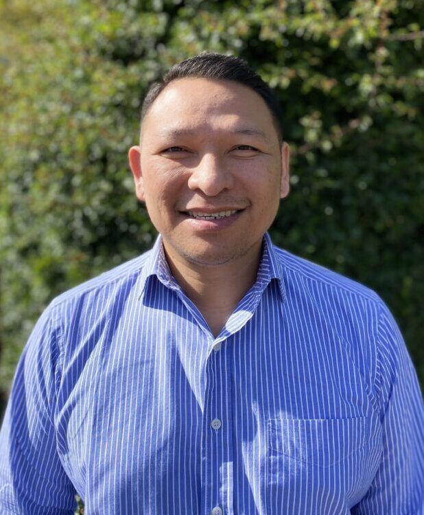 A man in a blue striped shirt is smiling for the camera.