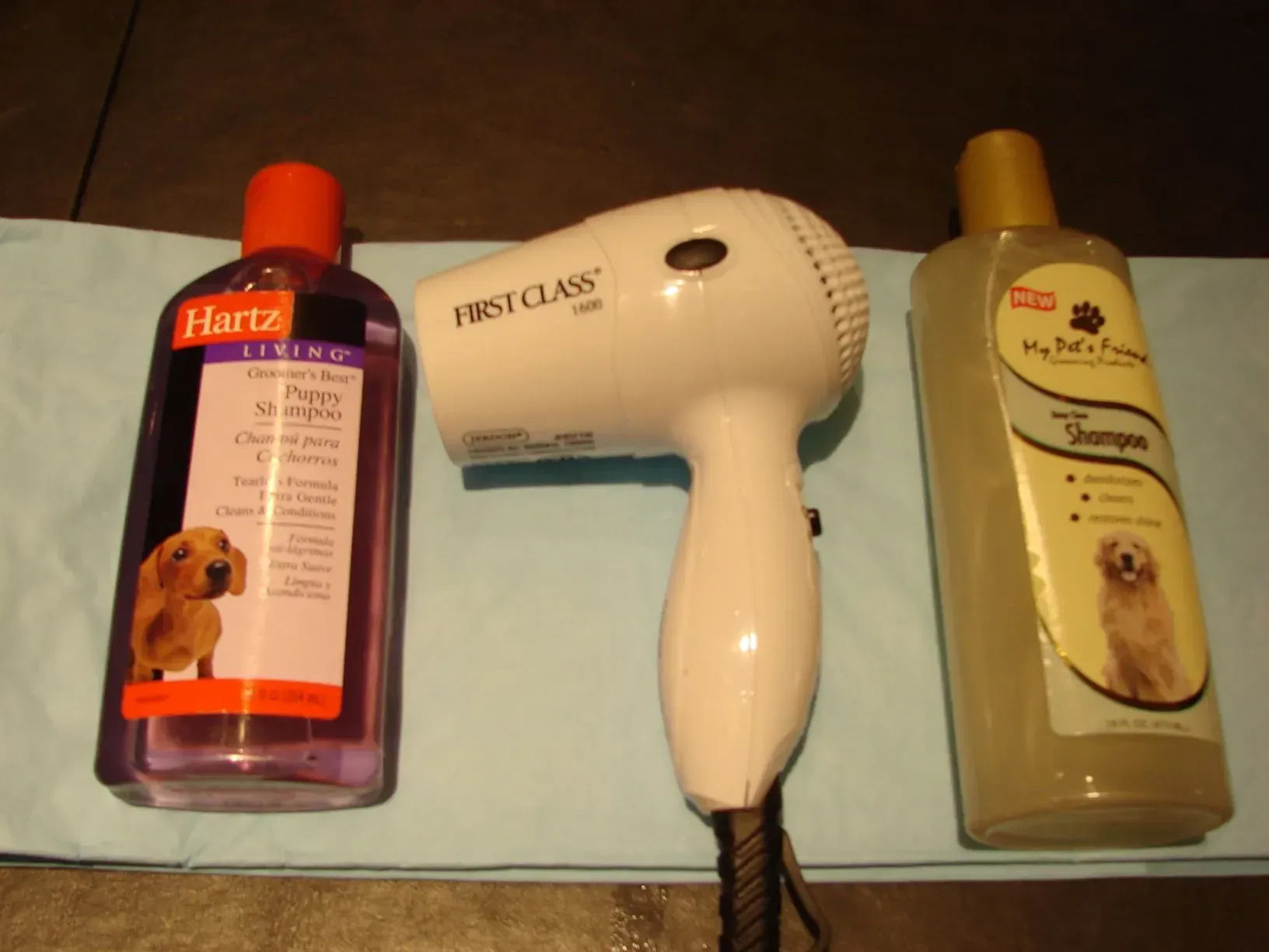 A bottle of hartz shampoo a hair dryer and a bottle of dog shampoo