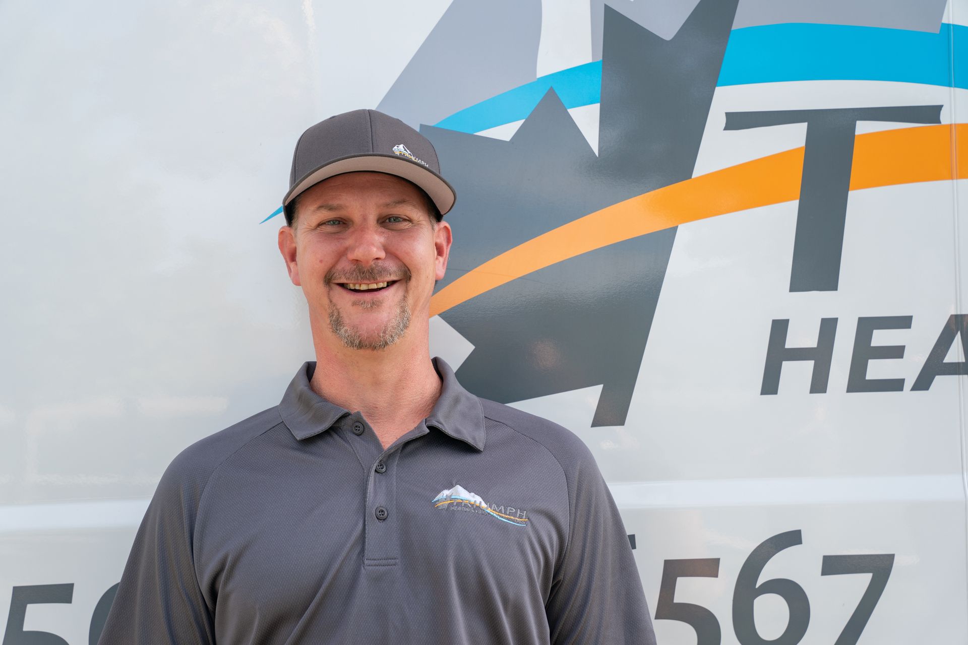 A man with a beard and sunglasses is standing in front of a white van.