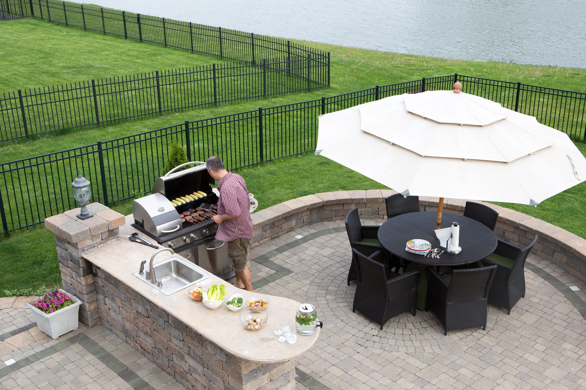 A man is grilling food on a patio next to a table and chairs.