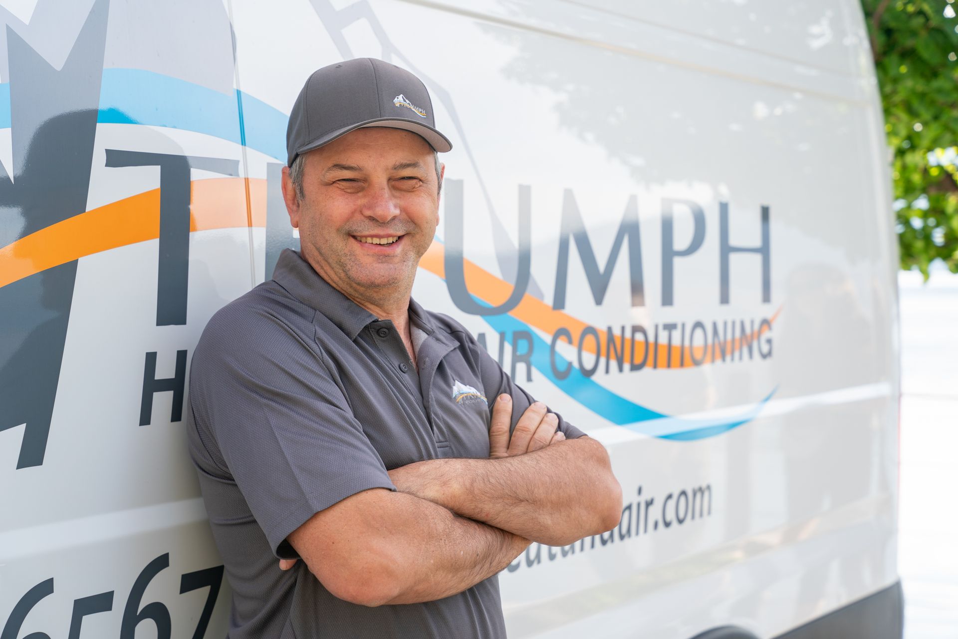 A man wearing a hat and a hoodie is smiling in front of a van.