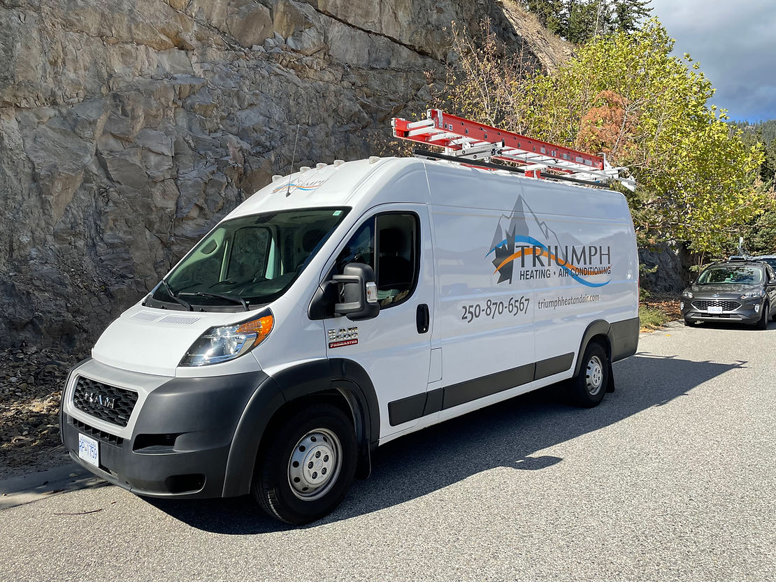 A white van with a ladder on top of it is parked in a gravel lot.