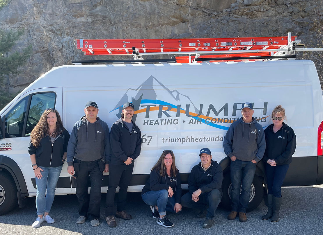 A group of people standing in front of a triumph heating and air conditioning van.