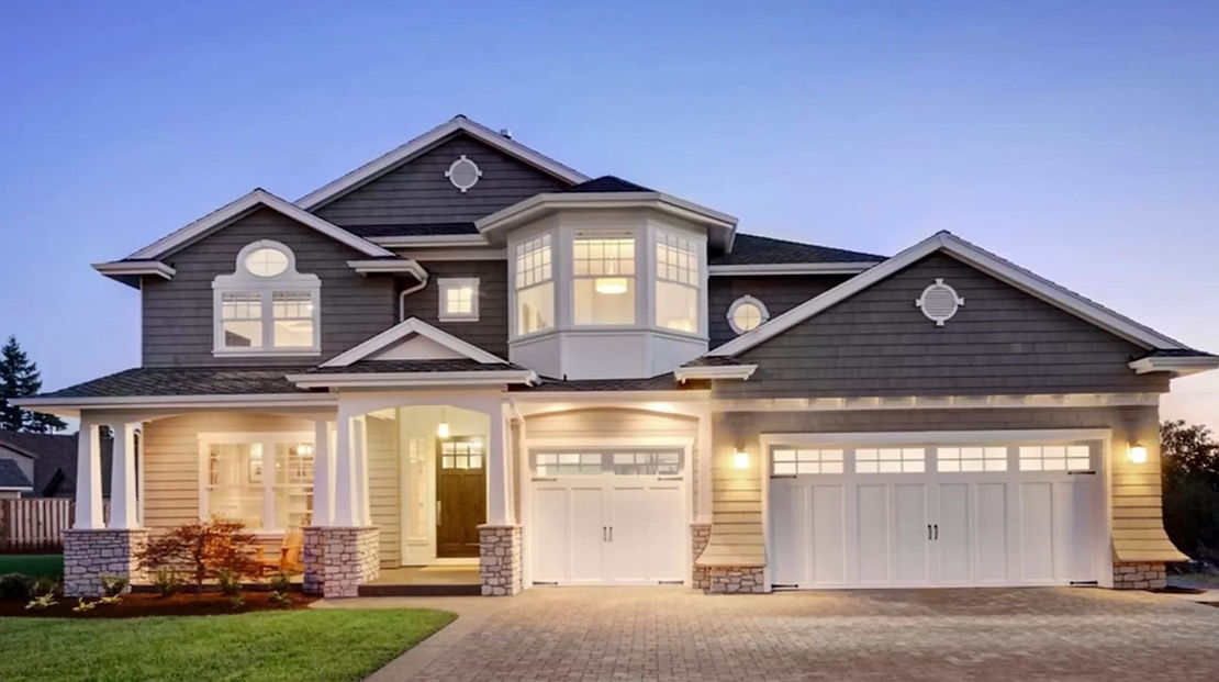 A large house with a large garage is lit up at night.