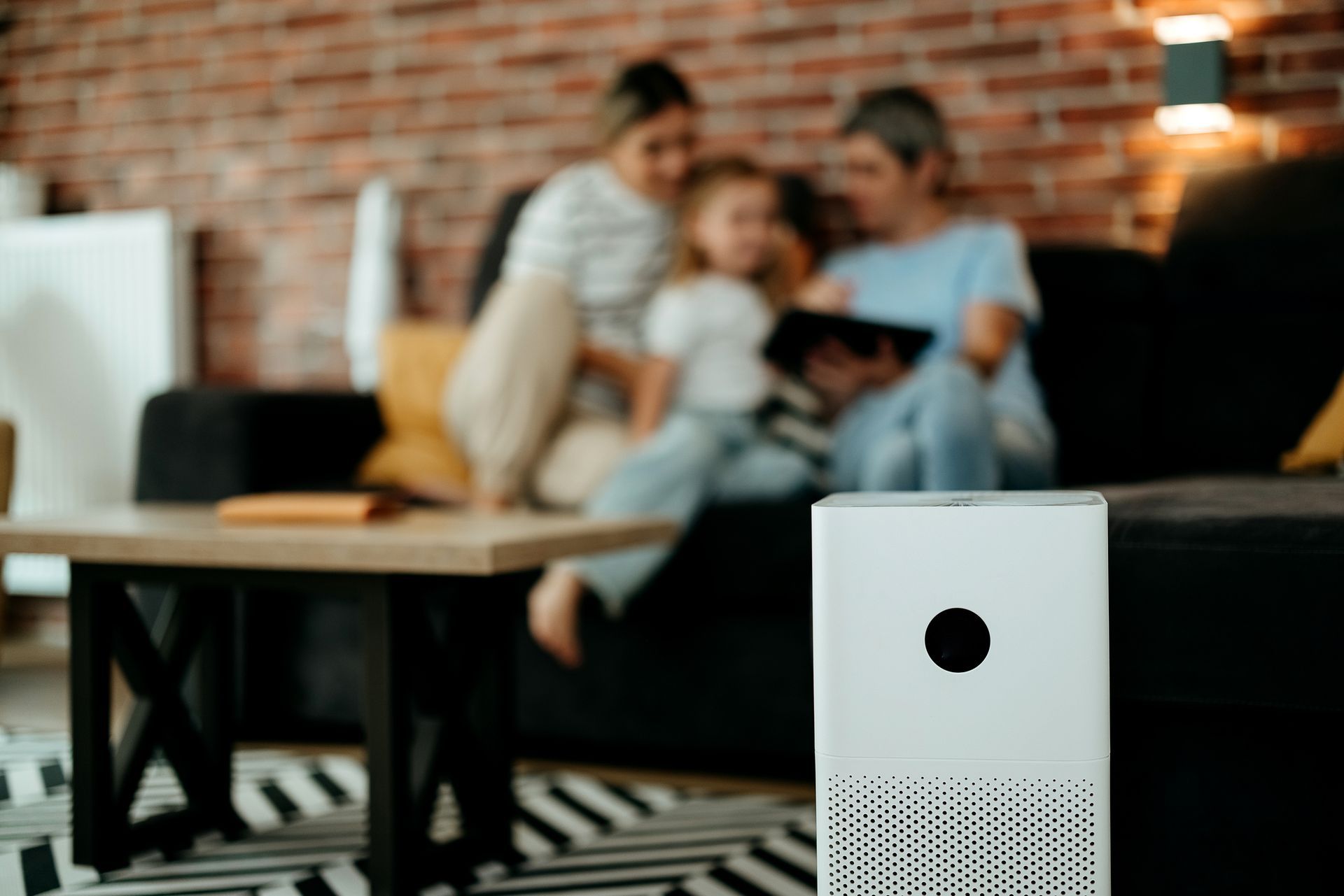 Family relaxing in living room with air purifier helping improve indoor air quality for asthma.