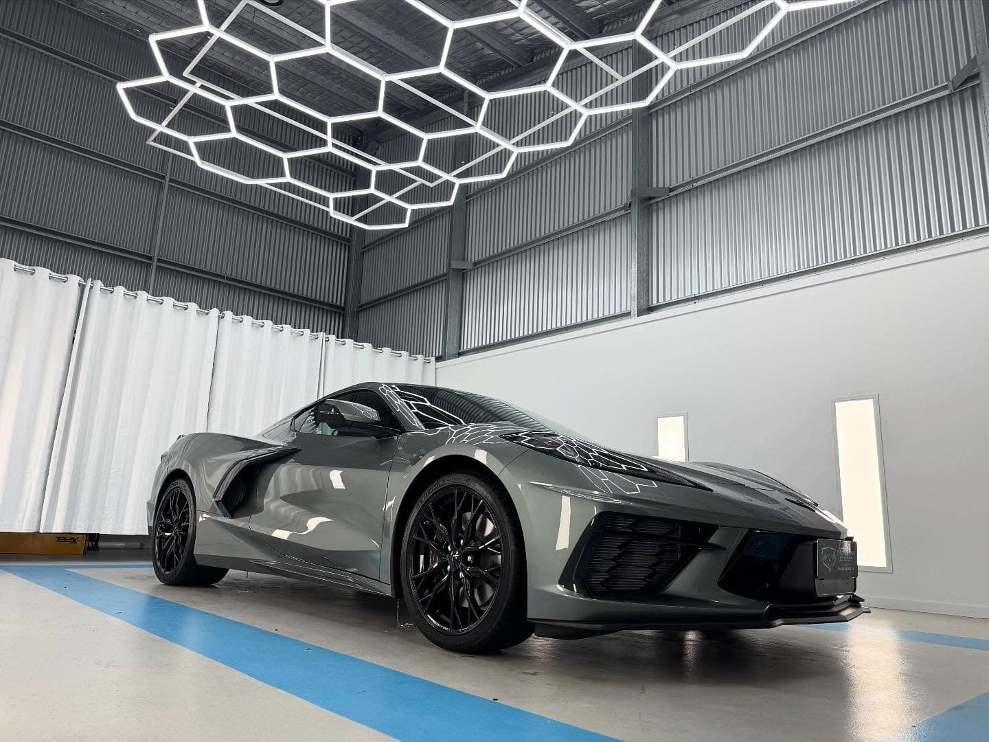 A gray sports car is parked in a garage.