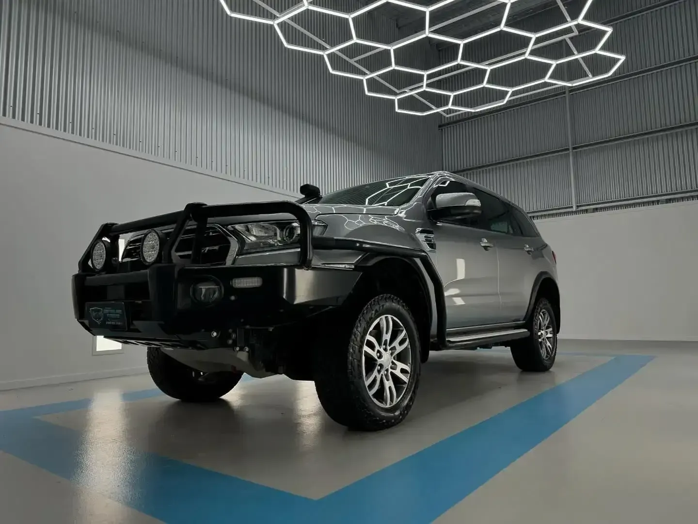 A Silver SUV is Parked in a Showroom With a Blue Stripe on the Floor — Bathurst Detailing Studio in Bathurst, NSW