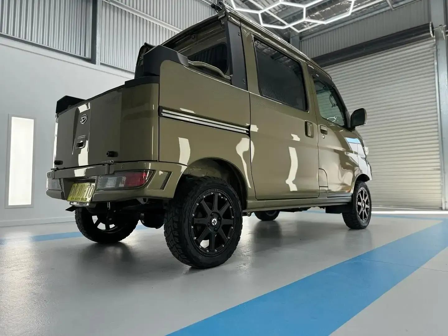 A Green Van is Parked in a Garage With a Blue Stripe on the Floor — Bathurst Detailing Studio in Bathurst, NSW