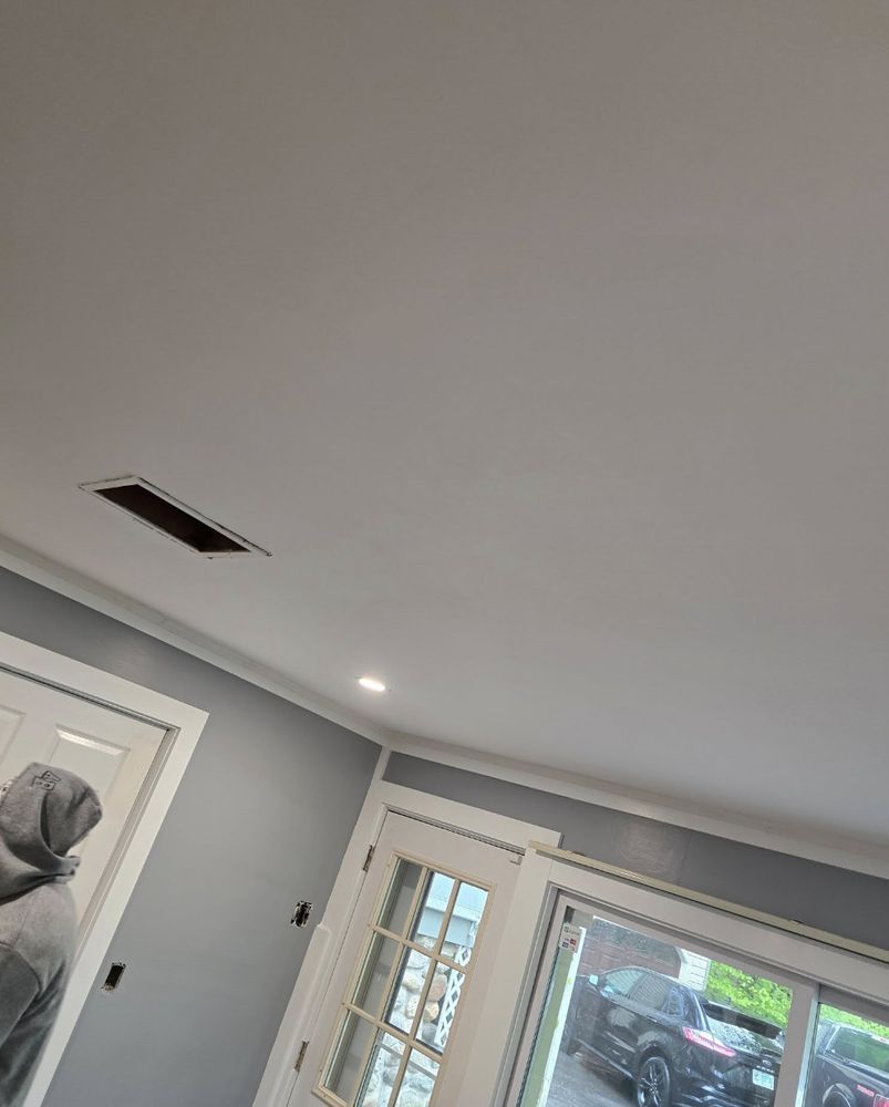 White ceiling with a rectangular vent. Blue walls, white trim, and a window. A person is partially visible.