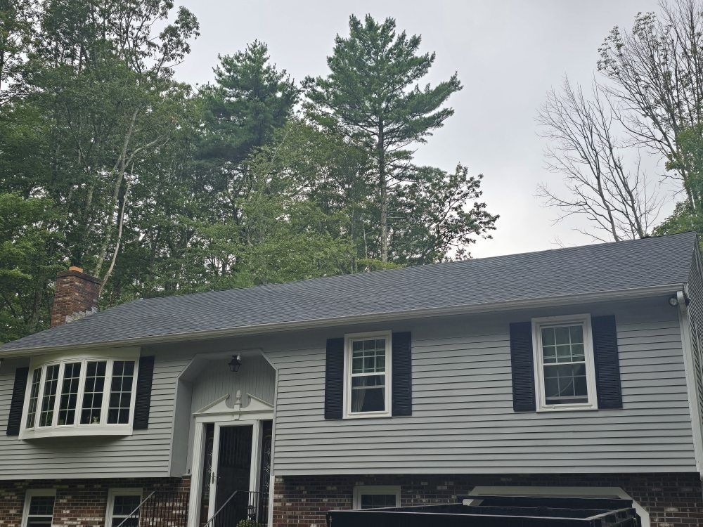 Gray house with black shutters, bay window, and a dark roof.
