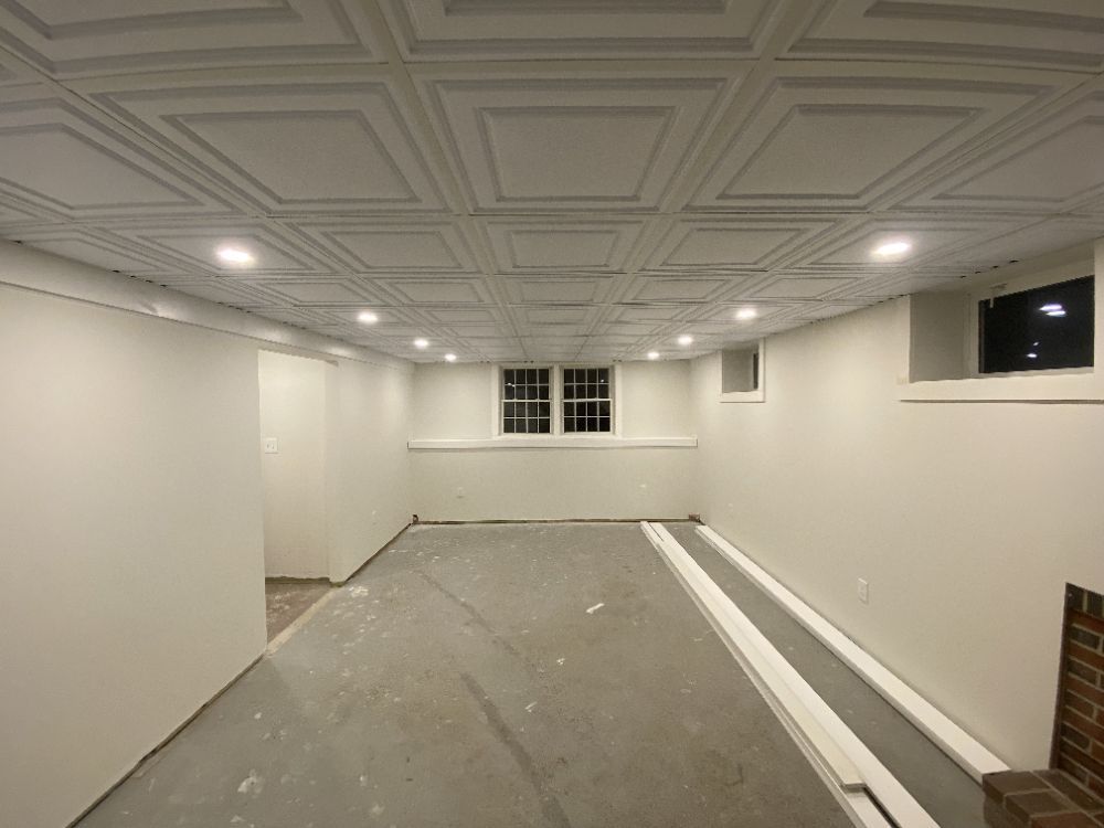 Finished basement with a patterned ceiling, recessed lights, and gray concrete floor.