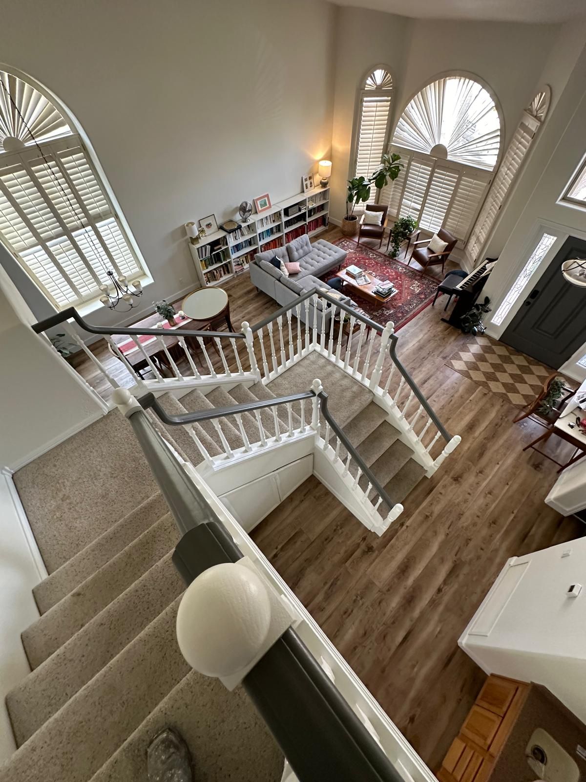 An aerial view of a living room and stairs from the second floor.