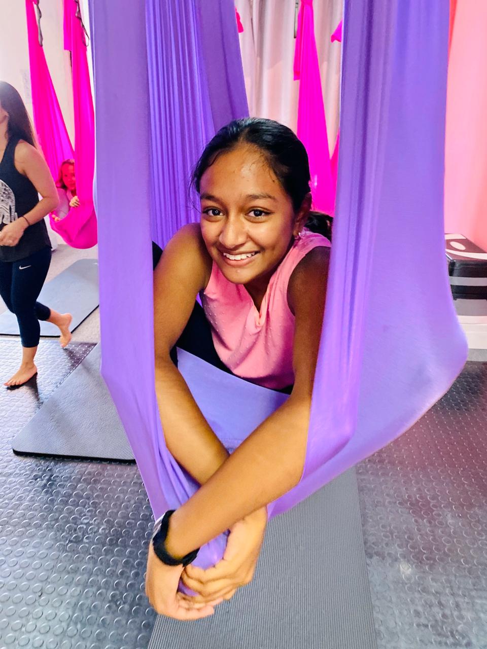 Girl sitting in aerial yoga hammock