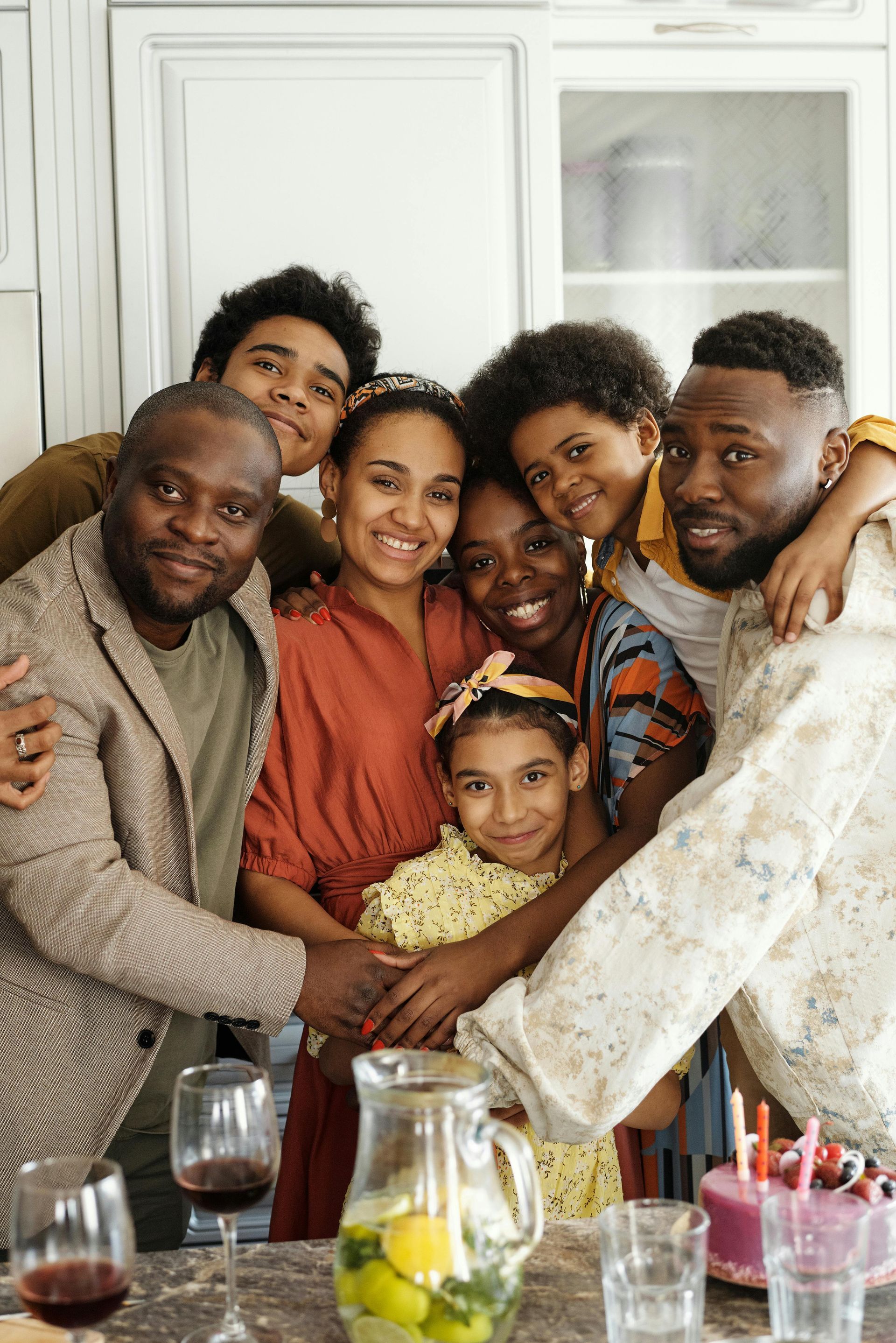 Group of people smiling and hugging around a kitchen counter at a family gathering