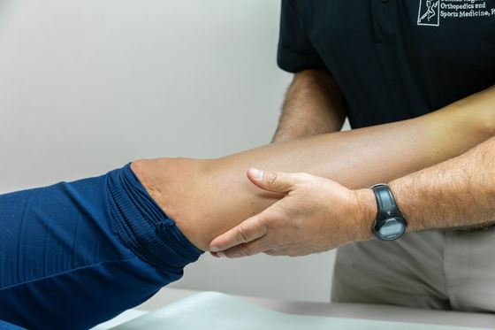 A man is giving a woman therapy on her knee.