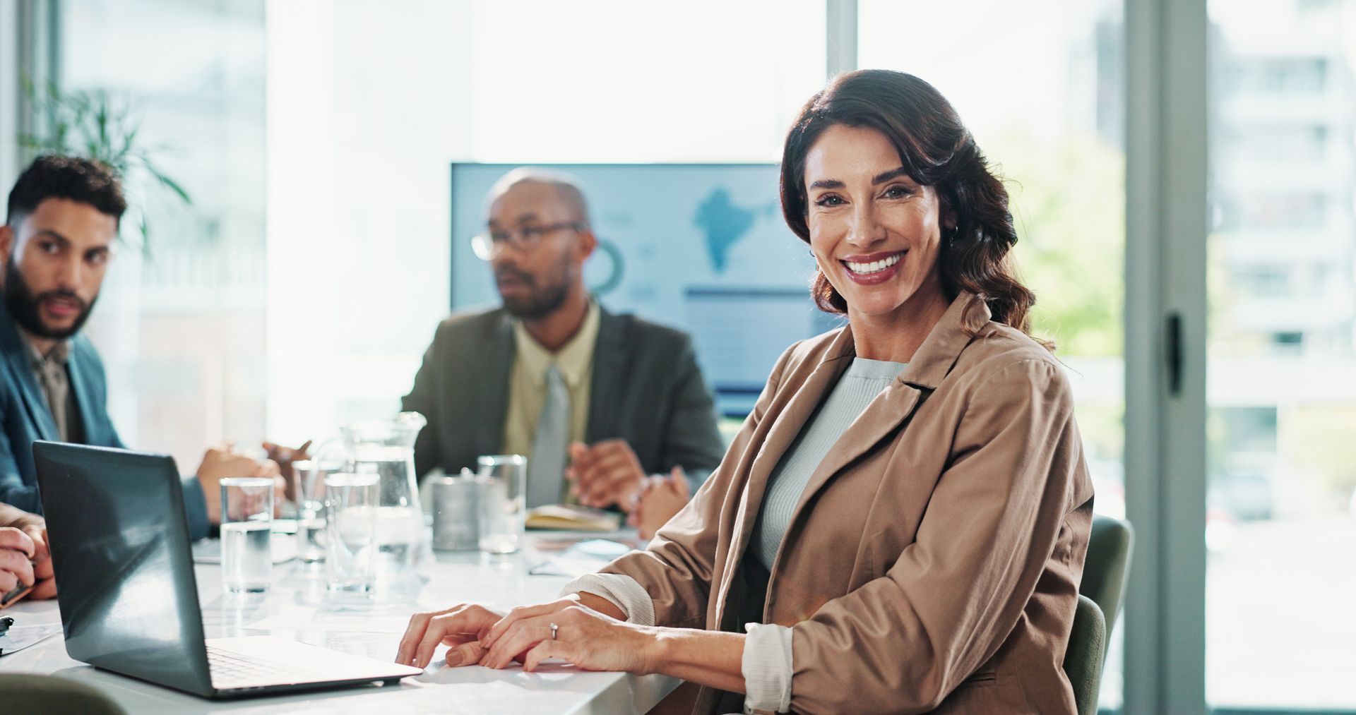 A woman is sitting at a table in front of a laptop computer.