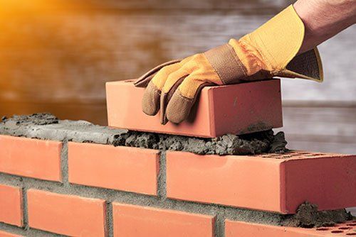Building Brick wall with gloved hands