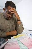 A man is sitting at a desk with a calculator and papers.