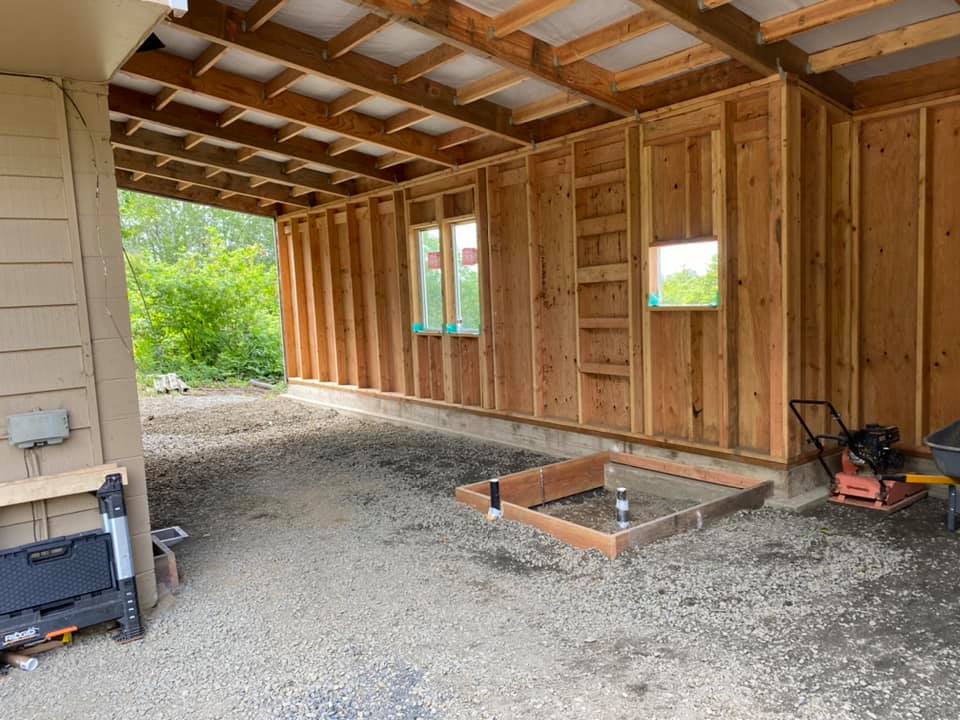 A wooden structure is being built in the backyard of a house.