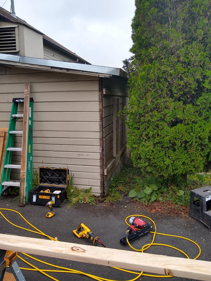 A ladder is sitting on the side of a building next to a wooden plank.