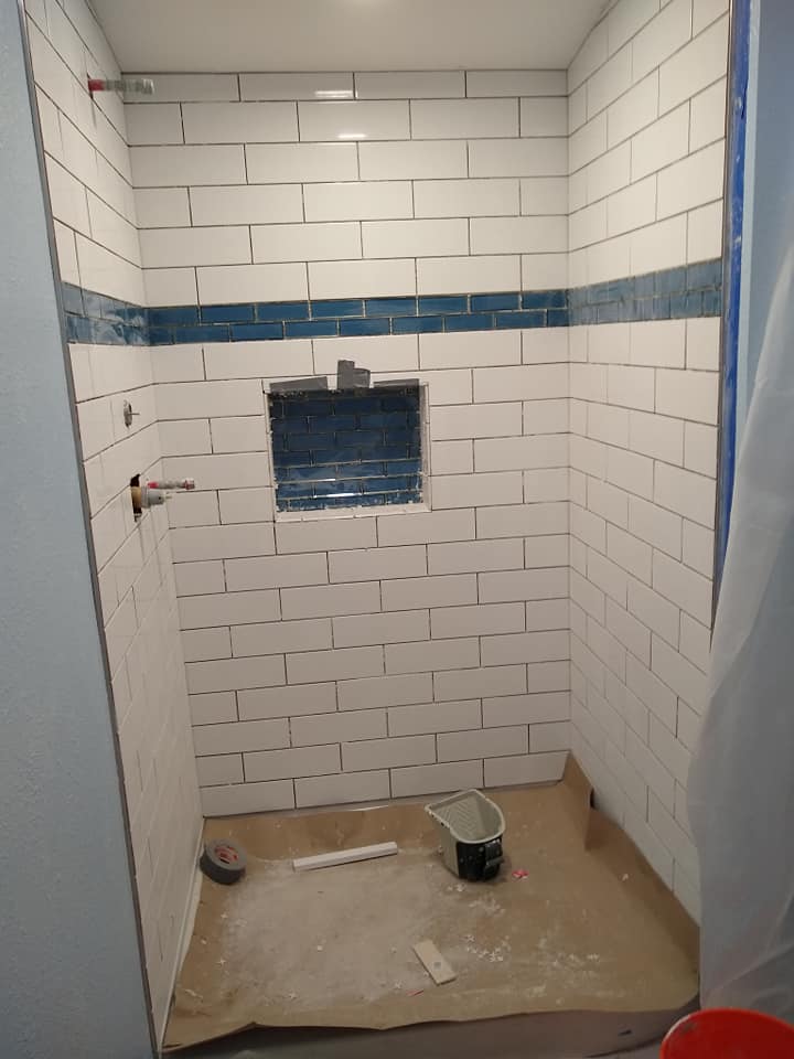 A bathroom with white tiles and blue trim is being remodeled.