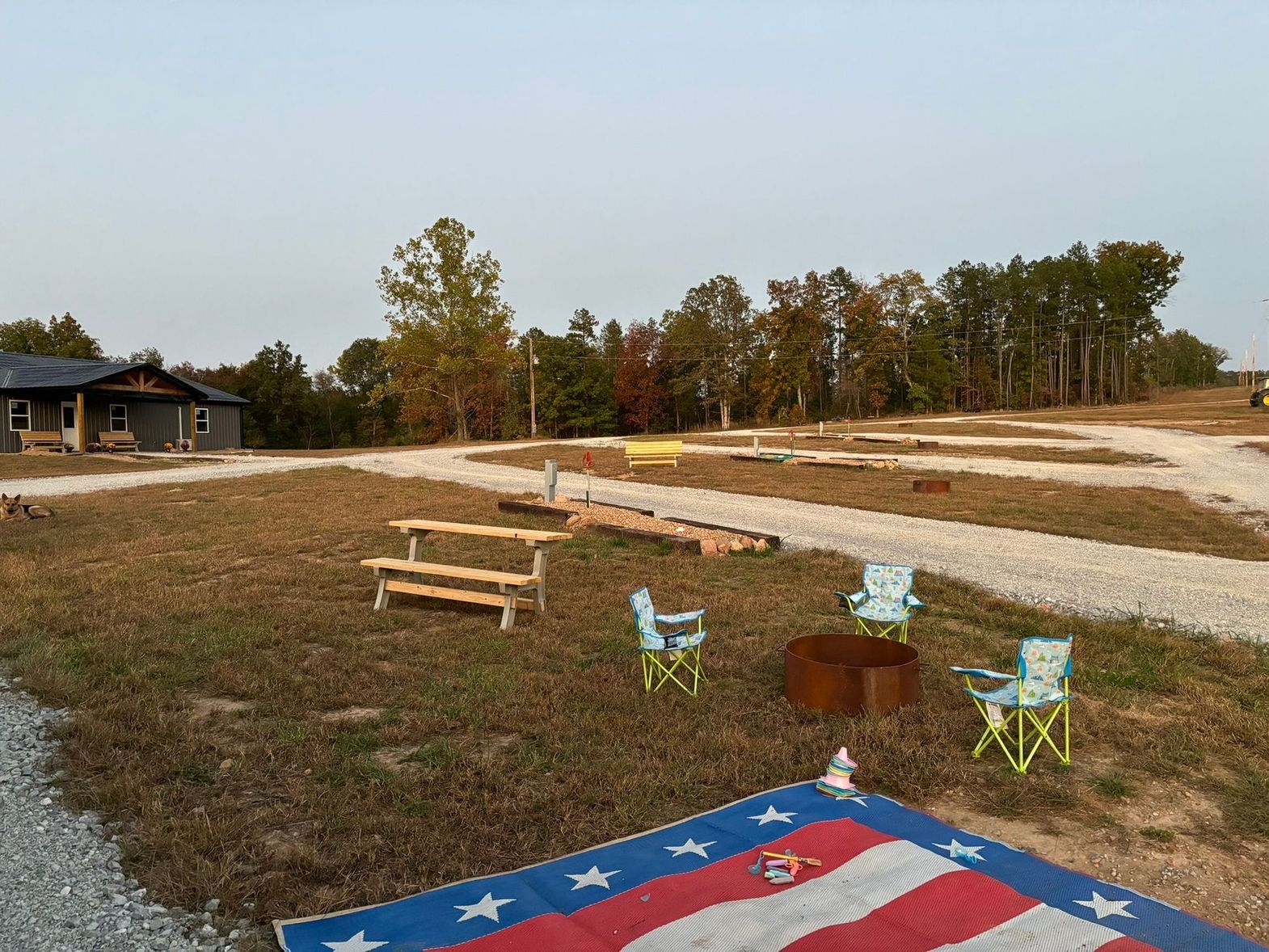 A picnic table and chairs are sitting on top of an american flag in a field.