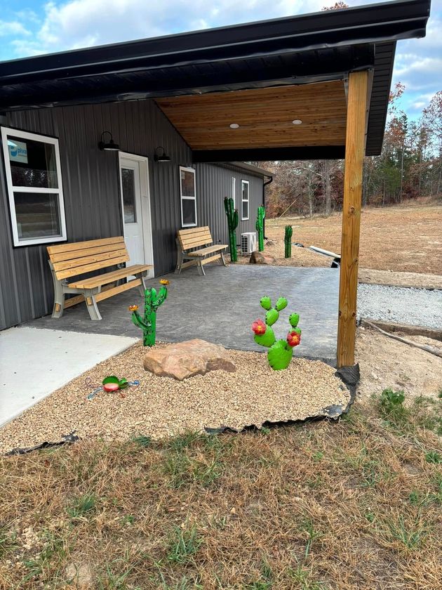 A covered porch with a bench and cactus in front of a house.