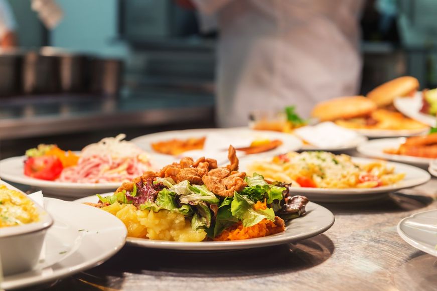 A chef is preparing plates of food in a restaurant kitchen.