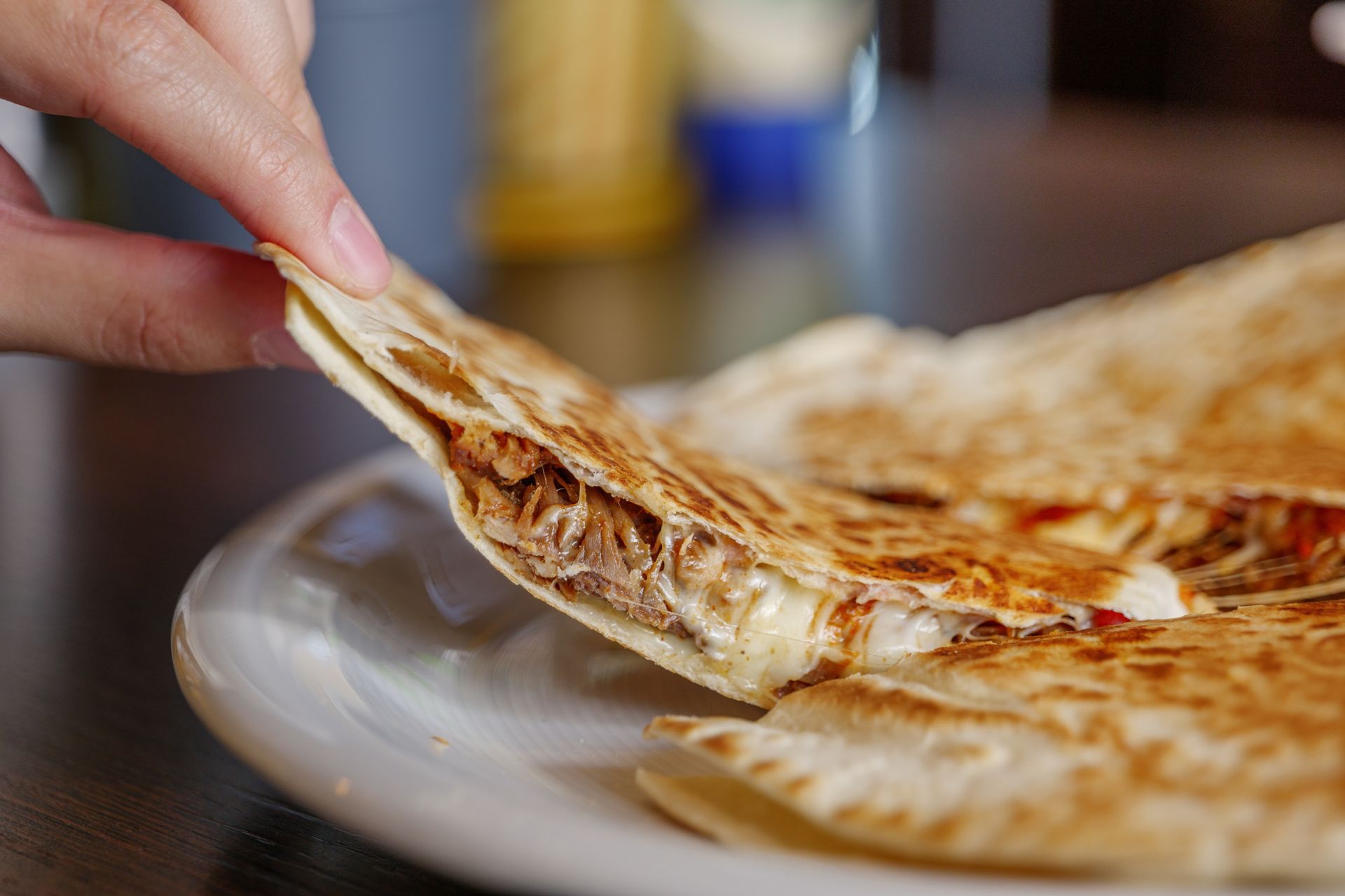 A person is taking a piece of quesadilla from a plate.