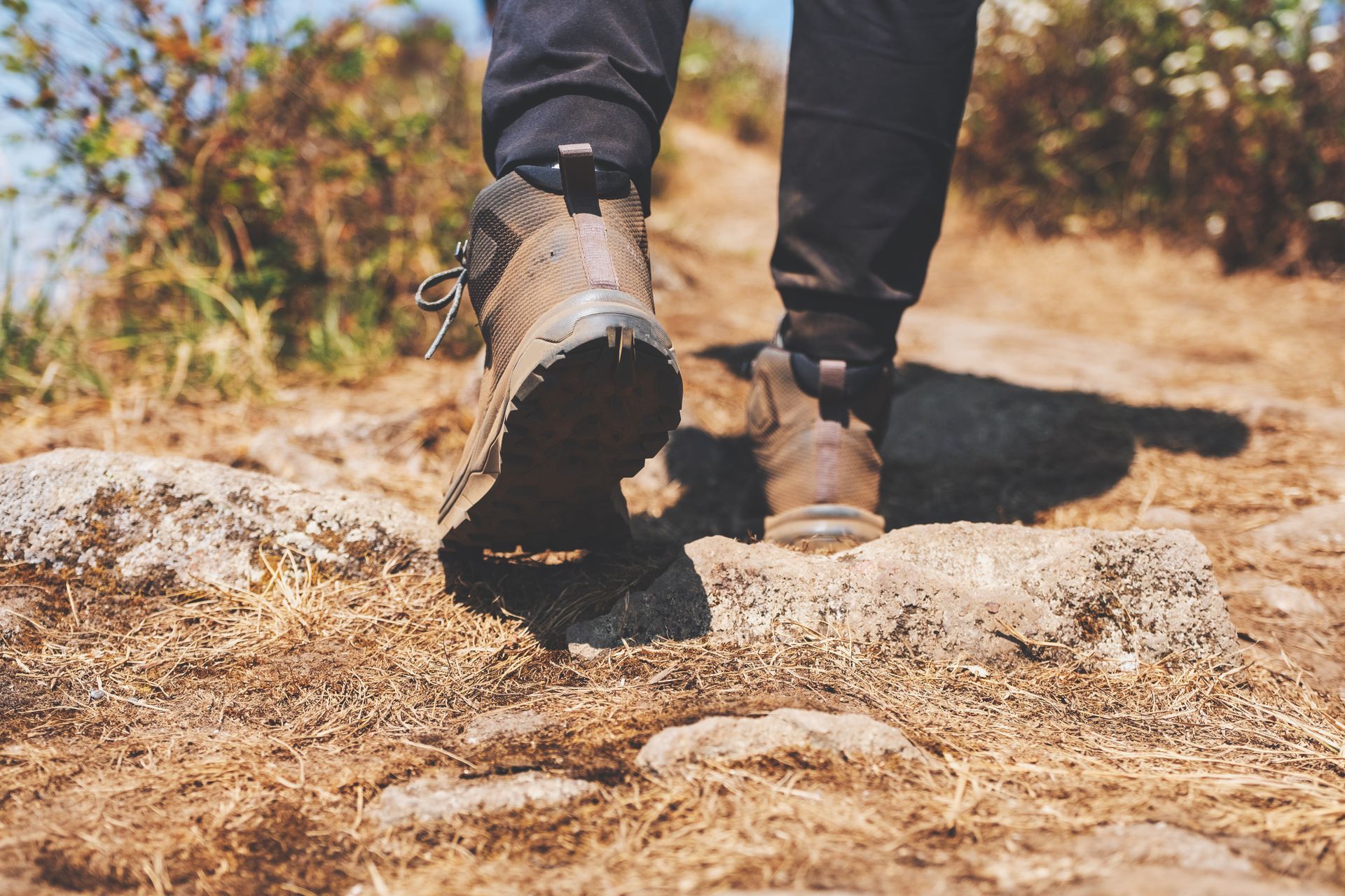 A person wearing hiking boots is walking on a rocky path.