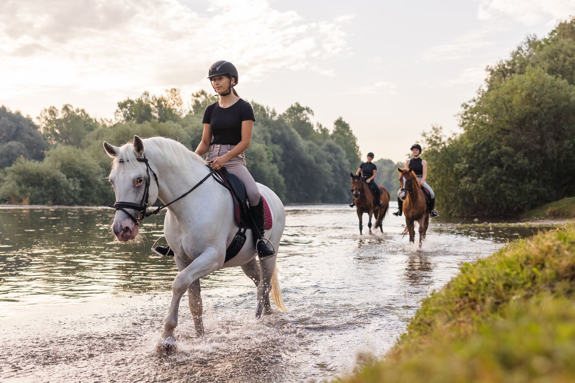 A group of people are riding horses through a river.