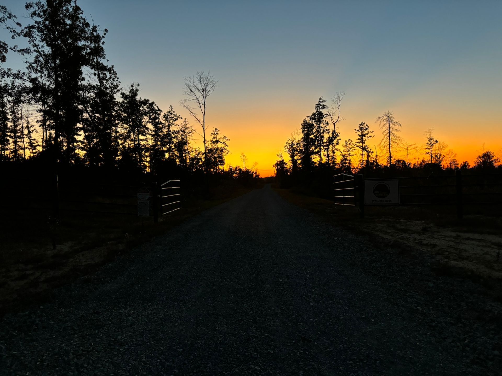 A dirt road with a sunset in the background