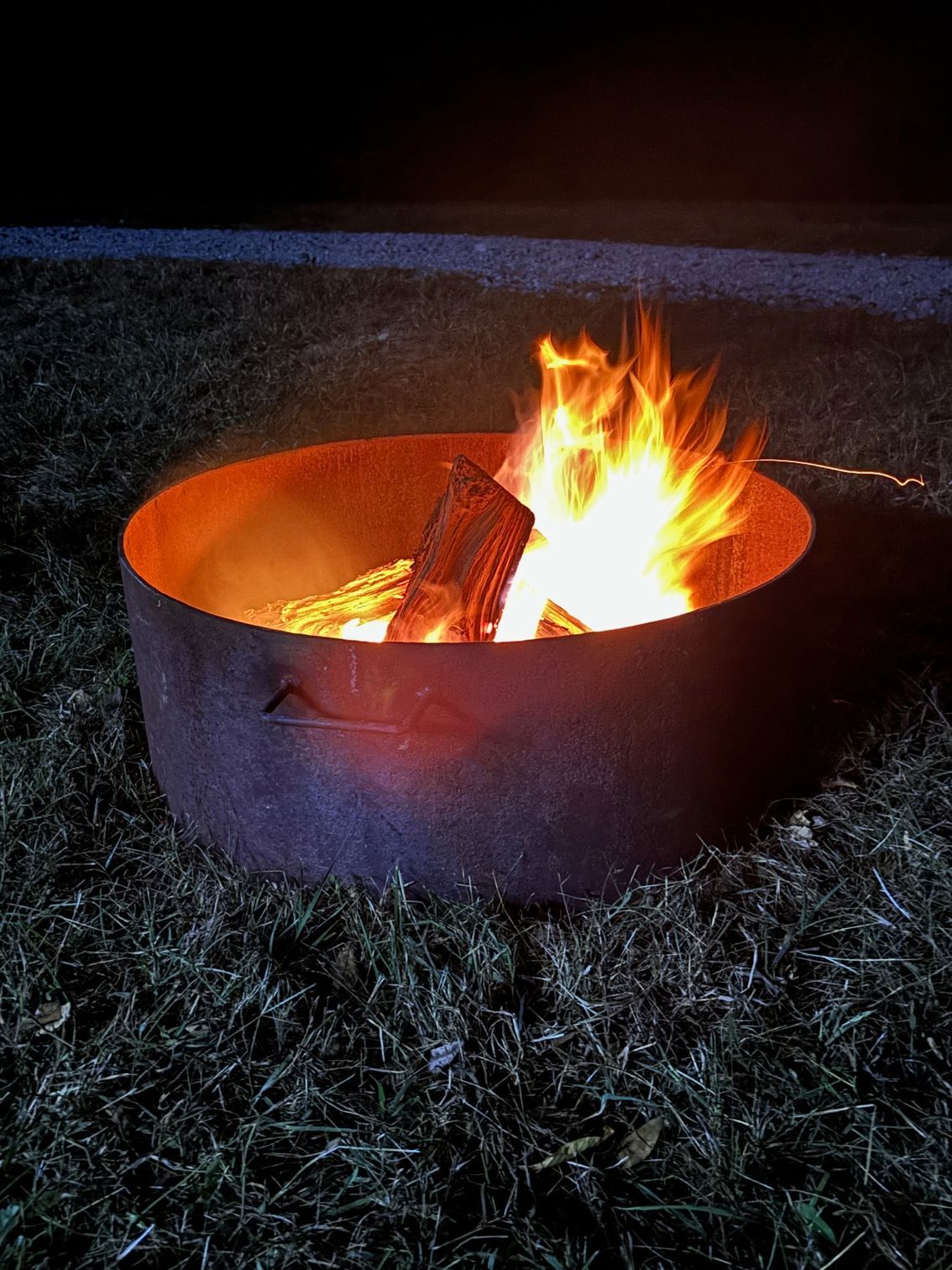 A fire pit is lit up in the grass at night