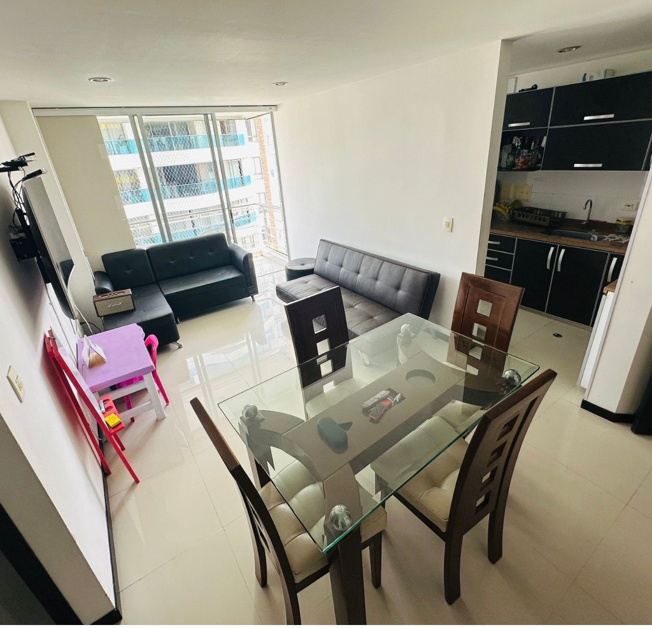 Sala de estar moderna: sofá gris, piso de madera, mesa de comedor redonda con sillas blancas, vista al dormitorio.