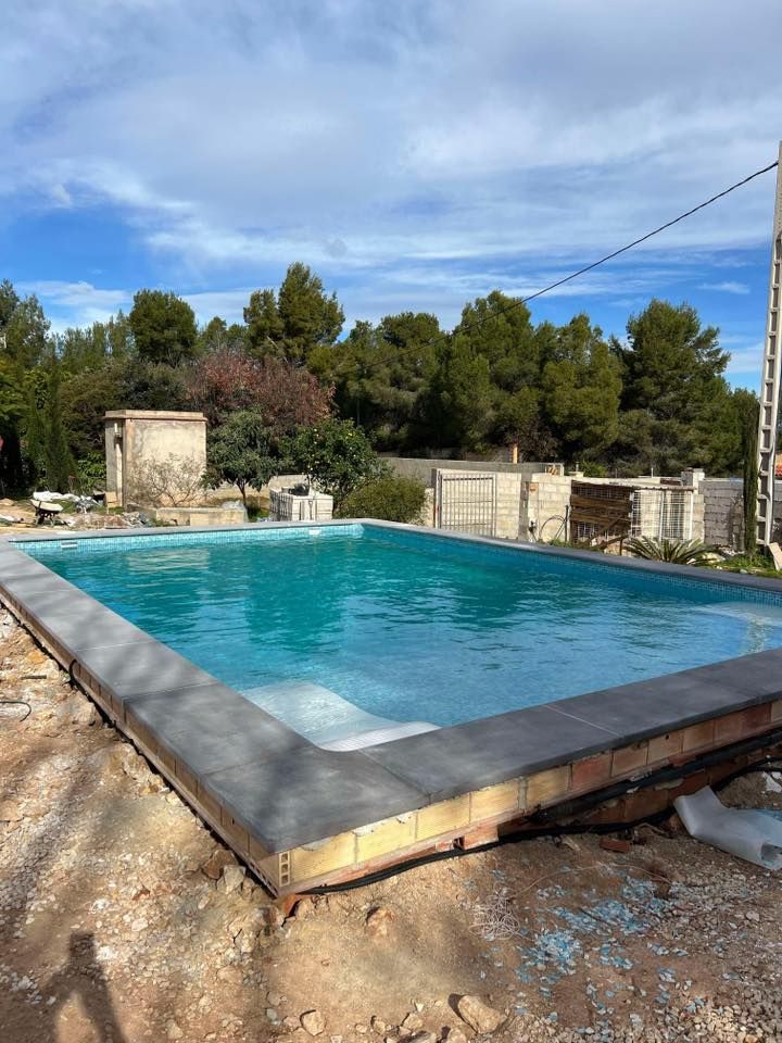 Swimming pool with turquoise water, grey border, and surrounding construction in an outdoor setting.