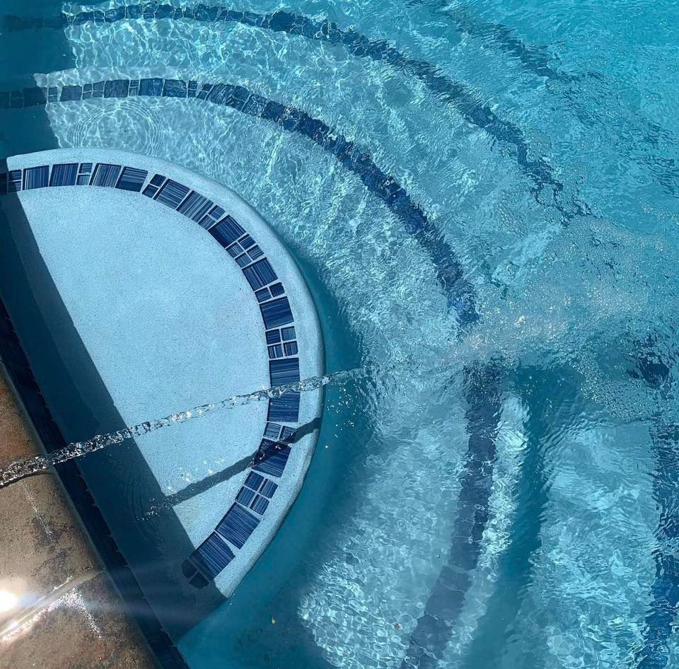 Pool with steps, light blue water, and a small water stream.