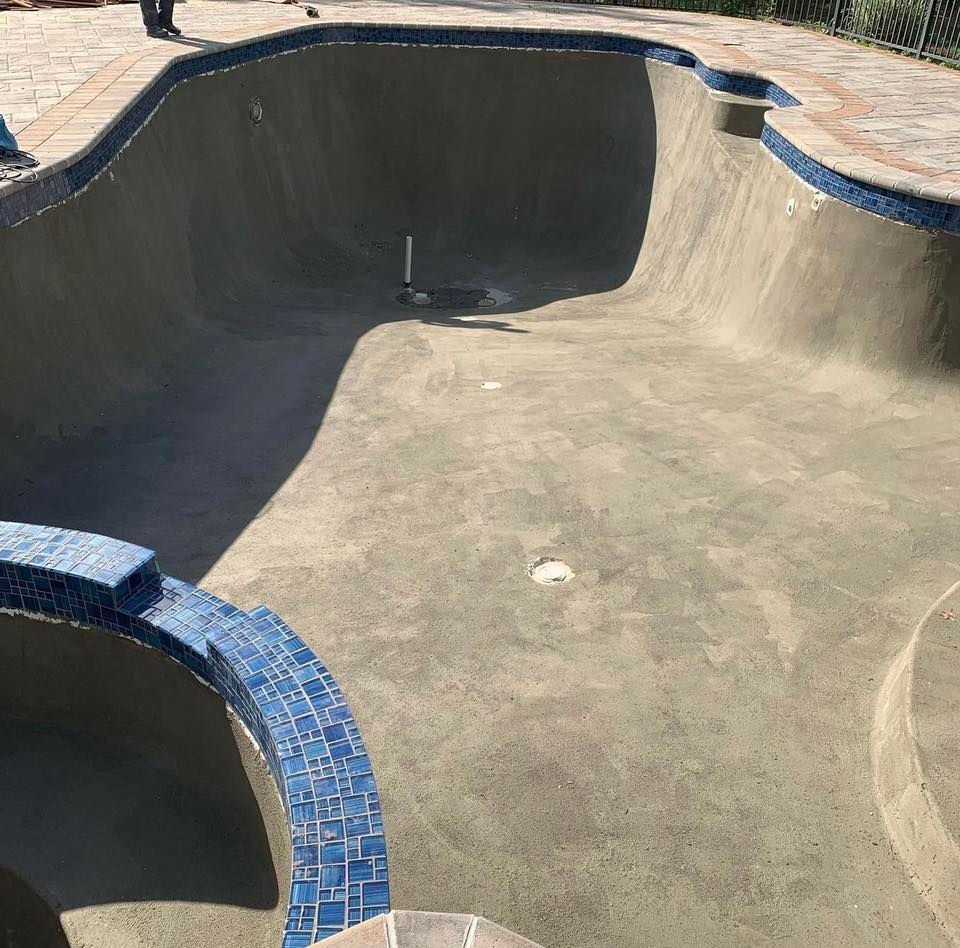 Empty concrete swimming pool with blue tiled edges.