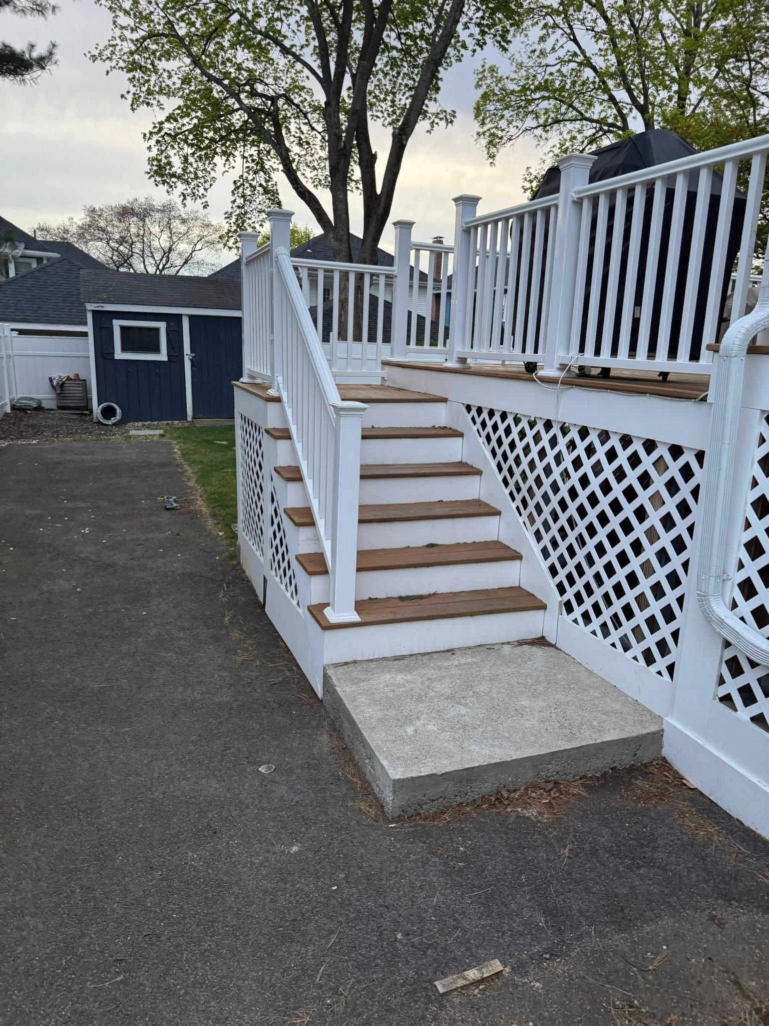 Deck with white railings and lattice, brown steps, and a concrete landing.