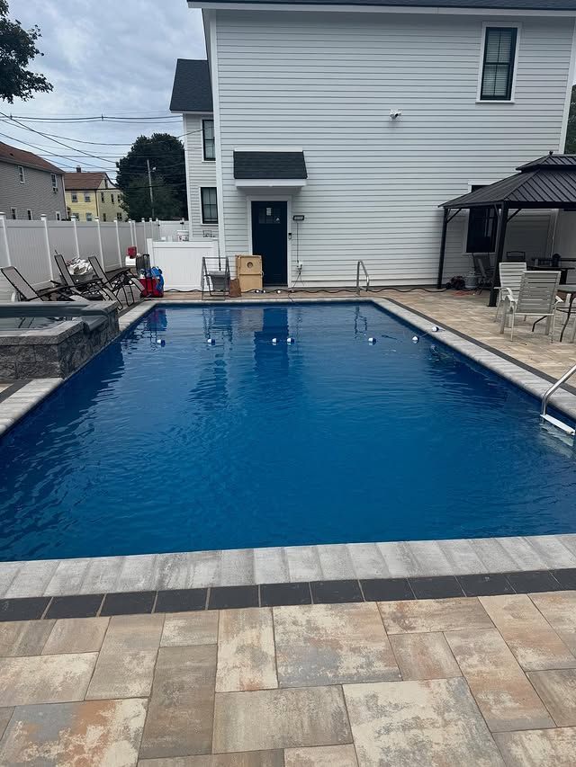 Backyard with rectangular pool, patio, gazebo, and a two-story white house.